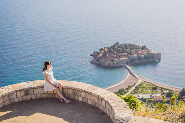 Woman tourist on background of beautiful view of the island of St. Stephen, Sveti Stefan on the Budva Riviera, Budva, Montenegro. Travel to Montenegro concept. - Foto, afbeelding