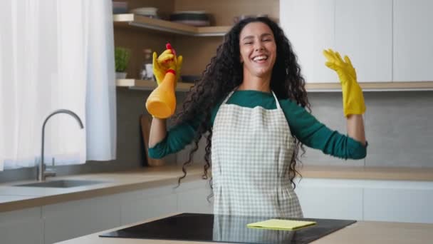 Радісна дружина домогосподарка гарненька мама арабський працівник одягає фартух, танцює в рукавичках з санітарним розпилювачем на сучасній квартирі чиста кухня, переходить на музику веселі прибирання домашніх обов'язків
 - Кадри, відео