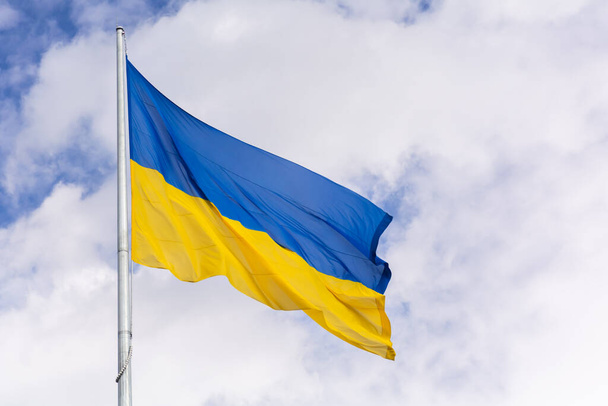 Estado amarillo y azul bandera de Ucrania en el fondo del cielo con nubes - Foto, imagen