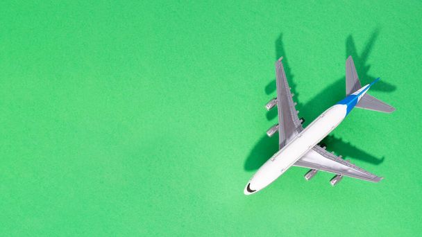Vista dall'alto di aereo modello bianco, giocattolo aereo su sfondo verde isolato. Posa piatta con spazio di copia. Bandiera di viaggio o viaggio - Foto, immagini