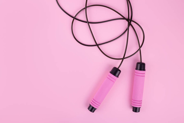 Fitness concept. Top view photo of pink skipping rope on isolated pastel pink background with copyspac - 写真・画像