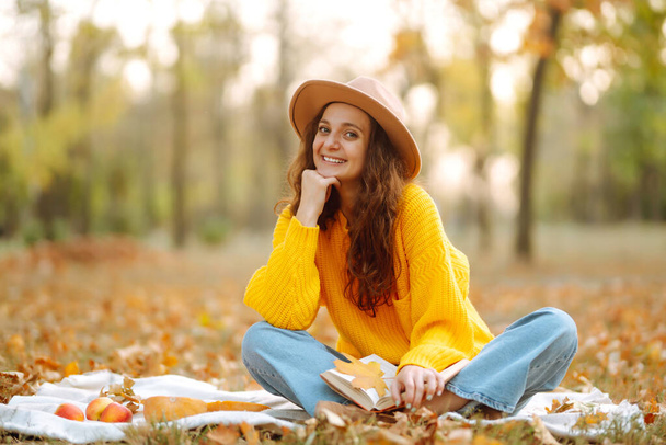 Fall picnic with pumpkin. Young woman resting in nature. Autumn harvest. People, lifestyle, relaxation and vacations concept.  - Foto, imagen