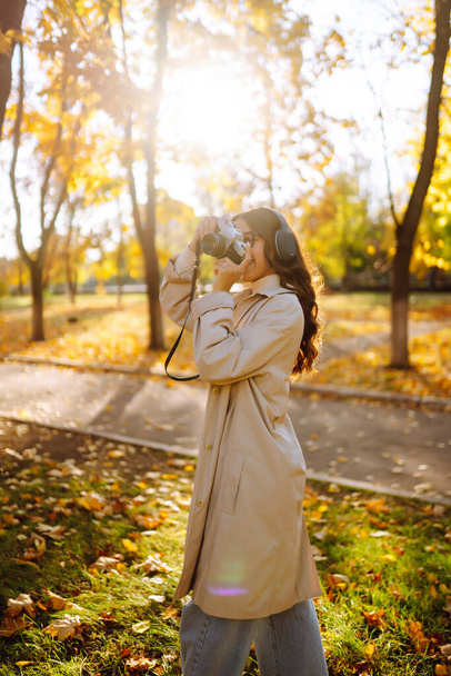 Portrait of  beautiful woman taking pictures in the autumn forest. Smiling woman enjoying autumn weather. Rest, relaxation, lifestyle concept. - Photo, Image