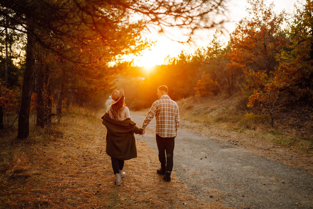 Jeune couple s'amusant à marcher et à se câliner sur le parc d'automne au coucher du soleil. Personnes, style de vie, détente et concept de vacances. - Photo, image