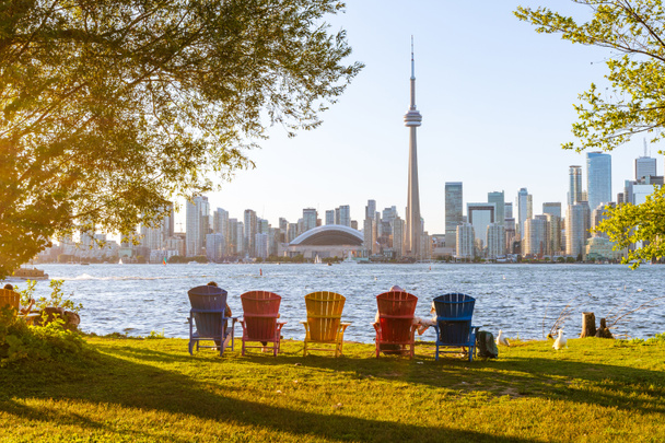 Barevné adirondack židle na Toronto Island Park při západu slunce. V pozadí panorama Toronto City. Ontario, Kanada. - Fotografie, Obrázek