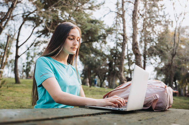 Estudiante universitaria riendo y usando su computadora en el parque universitario. Foto de alta calidad - Foto, imagen