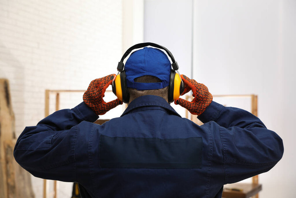 Worker wearing safety headphones indoors, back view. Hearing protection device - Foto, afbeelding