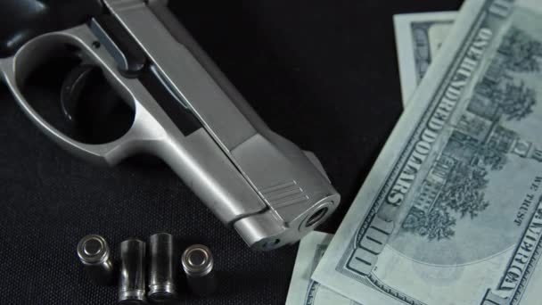 Billetes de dólar y pistola con balas en la mesa - Imágenes, Vídeo