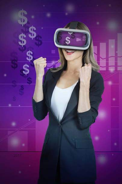 Picture of businesswoman wearing 3D glasses raises her fist as she succeeds in Metaverse business on multicolor background. - Foto, afbeelding