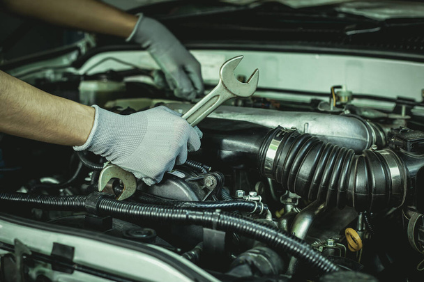 Mechanic works on the engine of the car in the garage.Concept of car inspection service and car repair service. - Zdjęcie, obraz