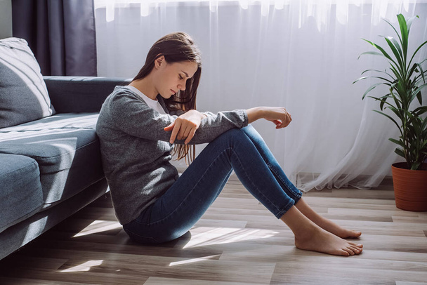 Depressed sad worried young brunette woman sitting on floor alone troubled with loneliness, upset about solitude mental problem, think of abortion regret bad mistake, breakup or divorce concept - 写真・画像