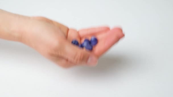 Uma mão das mulheres joga pílulas azuis em um fundo azul, close-up. - Filmagem, Vídeo