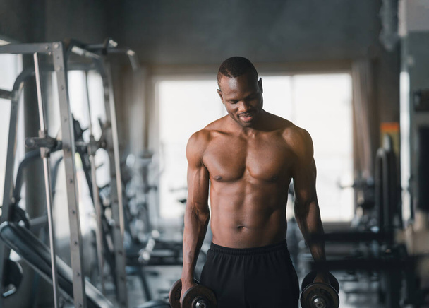 African sport man strong muscle working out excercise in weights with dumbbell at fitness room at the gym. Body building sport man fitness concept. - Fotoğraf, Görsel
