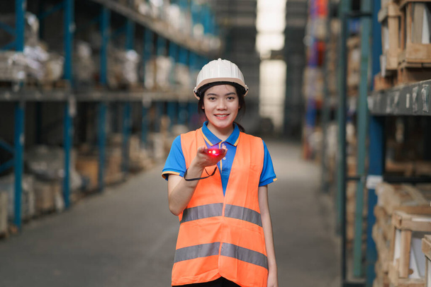 Portrait de jeune ouvrière asiatique utilisant un scanner de code à barres et souriant vérifiant les marchandises et le stock de rayonnages dans le magasin de l'usine d'entrepôt et souriant heureux. Entrepôt Concept logistique. - Photo, image