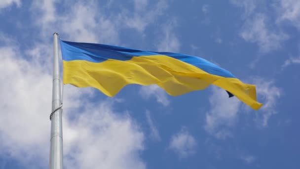 Bandera amarilla y azul del Estado de Ucrania ondeando en el viento sobre el fondo del cielo con nubes flotando a través del cielo - Imágenes, Vídeo