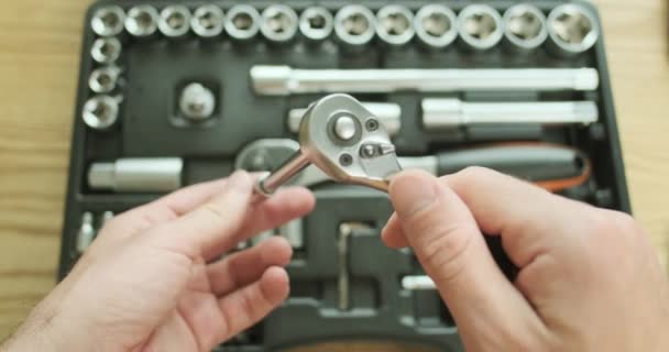 Auto mecânico desconecta o cabo de extensão de metal com uma pequena chave de catraca, coloca as ferramentas no caso. Demonstração do trabalho da chave, um conjunto de ferramentas em segundo plano, close-up, vista superior - Filmagem, Vídeo