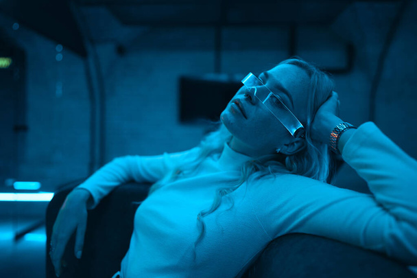Neon blue light falls on a young woman wearing futuristic glass glasses. High quality photo - Foto, Bild