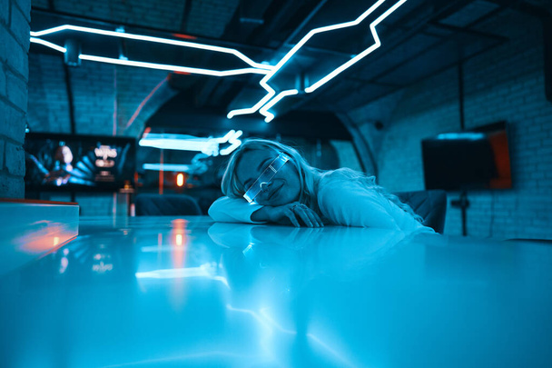 Neon blue light falls on a young woman wearing futuristic glass glasses. High quality photo - Φωτογραφία, εικόνα