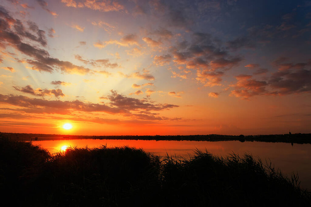 Viehättävä auringonnousu järven yli pilvien, auringon ja auringonvalon kanssa - Valokuva, kuva