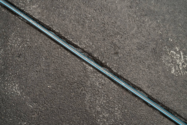 A trench on the pavement in asphalt with a cable, top view. - Foto, afbeelding