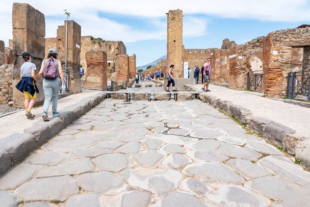 Een van de hoofdstraten met een voetgangersovergang met de openingen voor de wielen van de karren en koetsen in de stad Pompeii, Italië - Foto, afbeelding