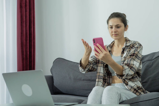 Dívka u laptopu drží telefon v rukou. Moderní práce. Generace Z. - Fotografie, Obrázek