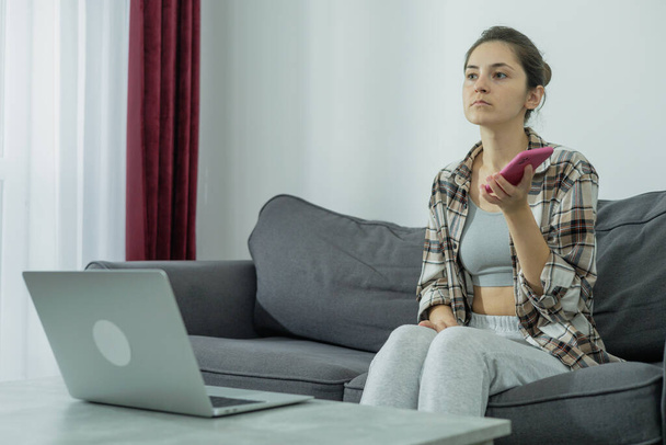 Das Mädchen am Laptop hält das Telefon in der Hand. Moderne Arbeit. Generation Z. - Foto, Bild