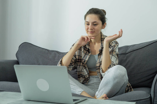 Front view of a girl at a laptop holding a phone in her hands. Communication online. Modern work. Green screen. Generation Z. Millennials - Zdjęcie, obraz