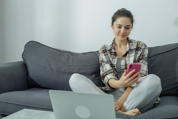 Vista frontal de uma menina em um laptop segurando um telefone em suas mãos. Comunicação online. Trabalho moderno. Tela verde. Geração Z. Millennials - Foto, Imagem