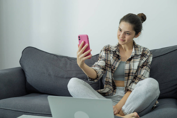 Vista frontal de una chica en un portátil sosteniendo un teléfono en sus manos. Comunicación en línea. Un trabajo moderno. Pantalla verde. Generación Z. Millennials - Foto, Imagen