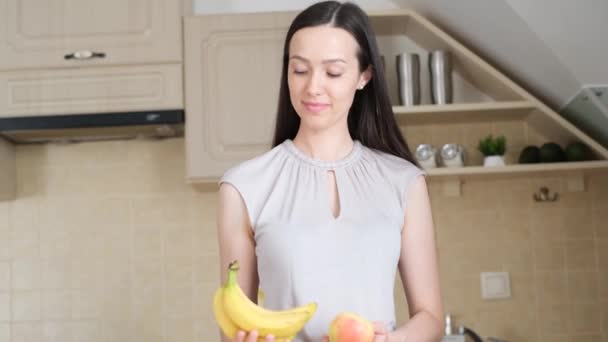 Une jeune femme tient dans ses mains une pomme et des bananes. Le concept de végétarisme. Régime aux fruits. Suivi avec un chiffre de perte de poids - Séquence, vidéo