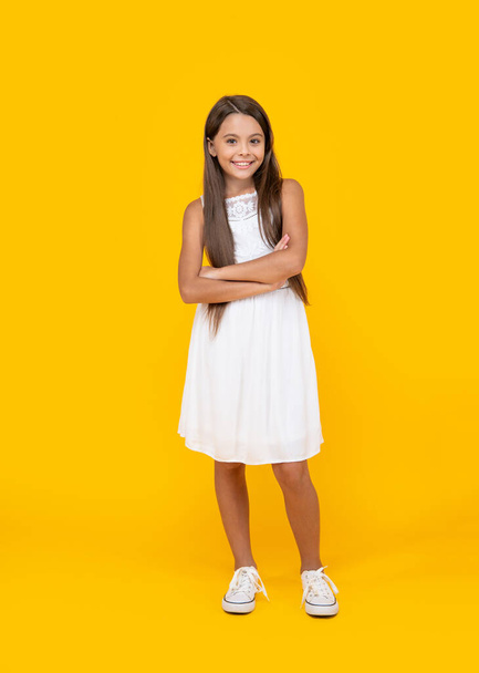smiling teen kid in white dress standing on yellow background. - Фото, изображение