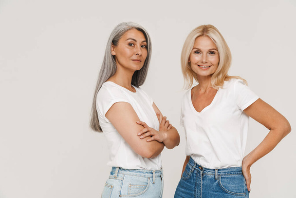Mature multiracial women with gray hair wearing t-shirts posing at camera isolated over white background - Foto, afbeelding