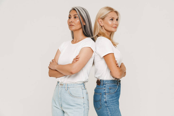 Mature multiracial women with gray hair wearing t-shirts posing at camera isolated over white background - Fotoğraf, Görsel