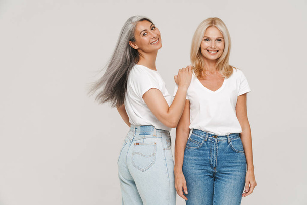 Mature multiracial women with gray hair wearing t-shirts posing at camera isolated over white background - Photo, image