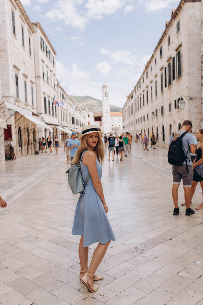 Dubrovnik, Хорватія - прекрасна пані туристка, мандрівник в синьому одязі і солом'яному капелюсі ходить по головній вулиці. Старе місто внесено до списку об "єктів всесвітньої спадщини ЮНЕСКО 1979 року в Європі. - Фото, зображення