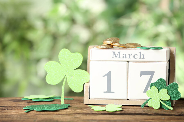 Composition with block calendar on wooden table against blurred greenery. St. Patrick's Day celebration - Foto, Imagem