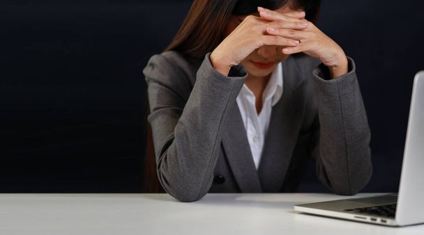 Mid adult businesswoman hands lying face down on table after bad news business failure or get fired and feeling discouraged, distraught and hopeless on blue background with computer and copy space. - Foto, Imagen