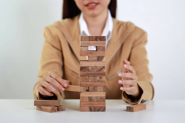 Zakenvrouw handen in klassieke suite zitten en spelen of controleren houten blok domino 's op tafel van zakelijke risico' s, Investment Insurance of business risk control concept - Foto, afbeelding