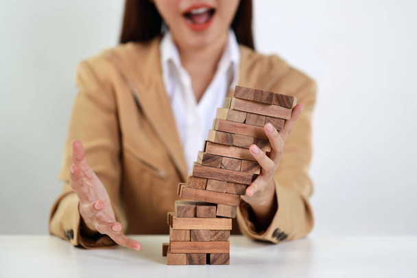 Businesswoman hands in classic suite sitting and stopping falling wooden block dominoes on table from business risk, Investment Insurance or business risk control concept - Fotó, kép