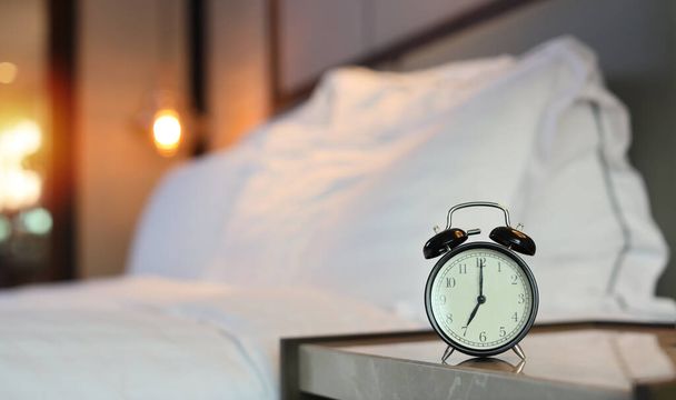 Siete horas reloj despertador imagen en el dormitorio con cama borrosa imagen de fondo - Foto, imagen