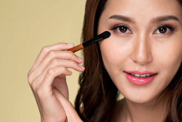 Closeup ardent young woman with healthy fair skin applying her eyeshadow with brush. Female model with fashion makeup. Beauty and makeup concept. - Foto, immagini