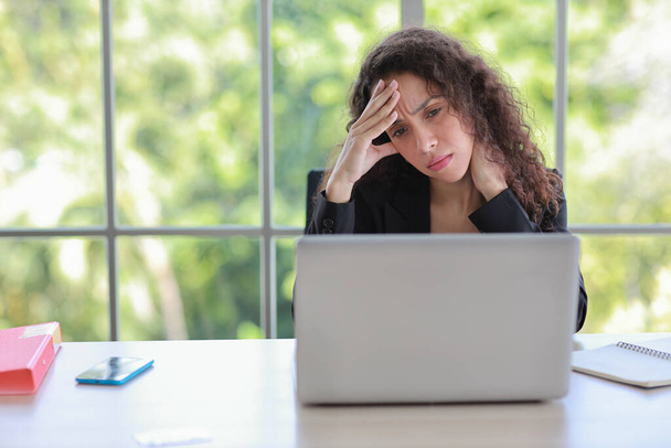 Mid adult businesswoman touching her head on table in office after bad news business failure or get fired and feeling discouraged, distraught and hopeless in modern office.  - Photo, Image