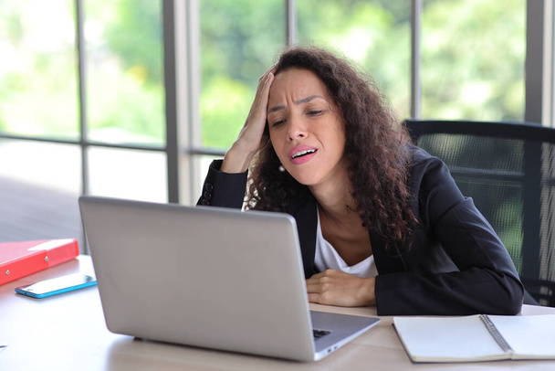 Mid adult businesswoman touching her head on table in office after bad news business failure or get fired and feeling discouraged, distraught and hopeless in modern office.  - Photo, Image