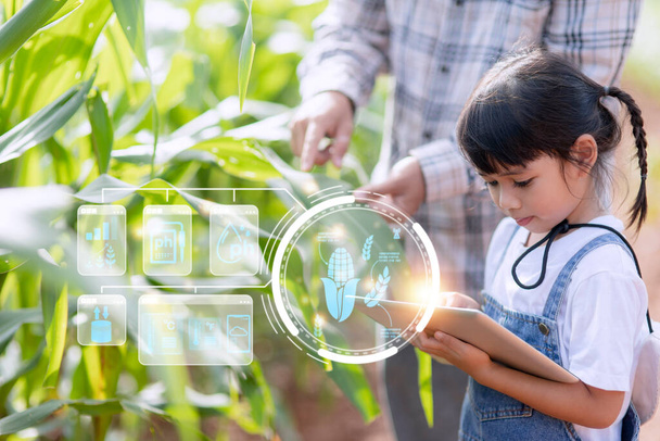 Das kleine Mädchen nutzt ein Tablet, um das Wachstum der Pflanzen in der landwirtschaftlichen Parzelle zu analysieren und das landwirtschaftliche Technologiekonzept visuell darzustellen. Smart Farming Lernkonzept - Foto, Bild