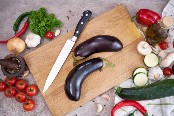 eggplant on wooden cutting board and vegetables at domestic kitchen. - Foto, imagen