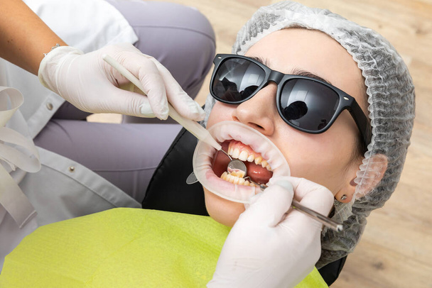 Fogorvos vizsgálja a betegek száját fogászati tükörrel a klinikán. Ellenőrzési koncepció - Fotó, kép