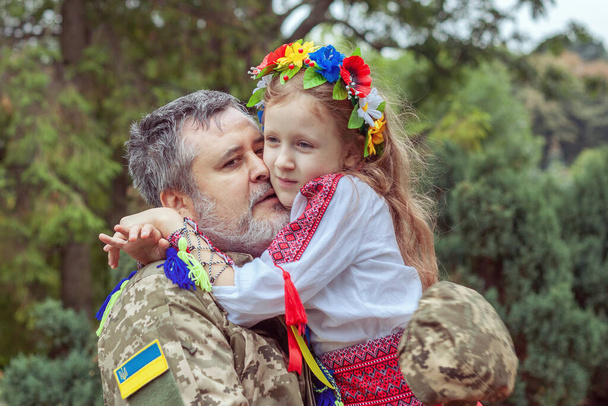 Portrait of a Ukrainian soldier with his little daughter. Long-awaited meeting. - Foto, afbeelding