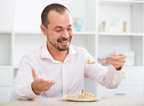 Positive young man ready to eat oat porridge in office - Фото, зображення