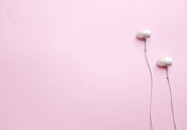 Z powyższych białych słuchawek, słuchawki, słuchawki ze słuchawkami na odizolowanym różowym pastelowym tle - Zdjęcie, obraz